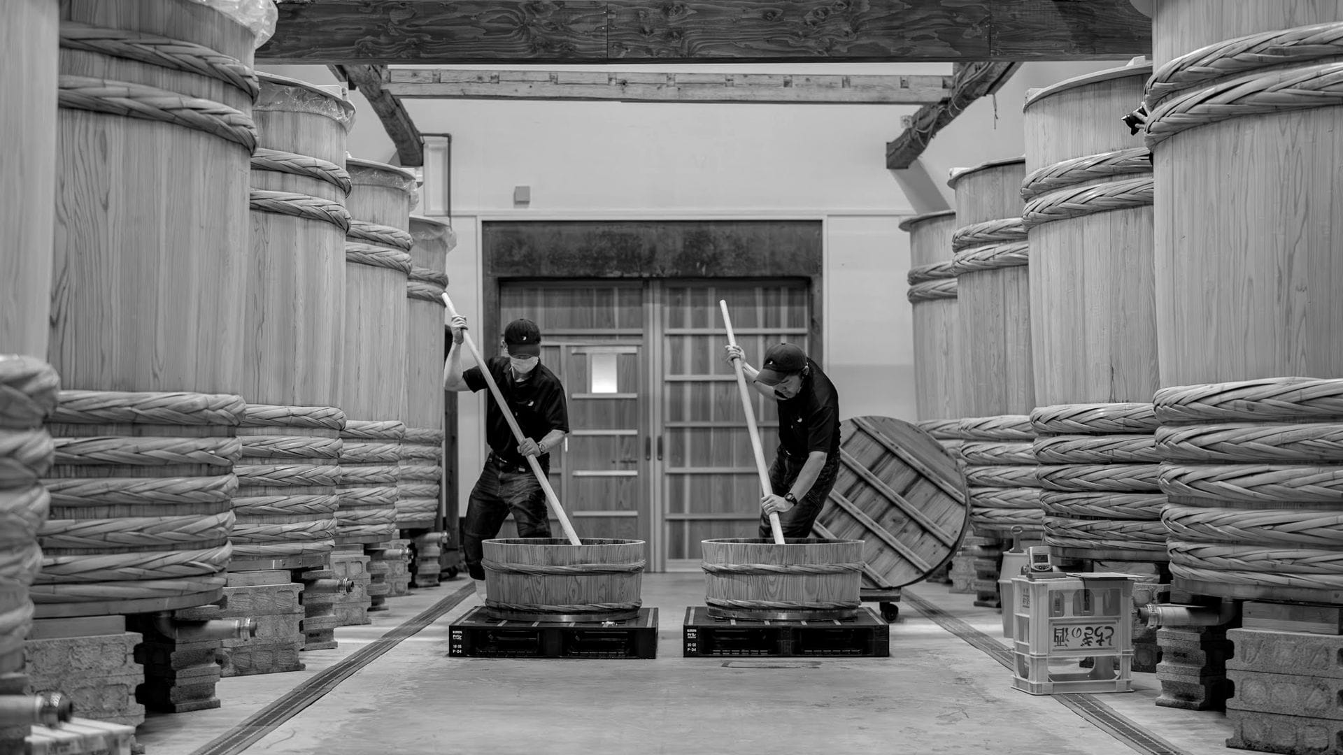 A brewer stirring the mash in a brewery lined with wooden vats
